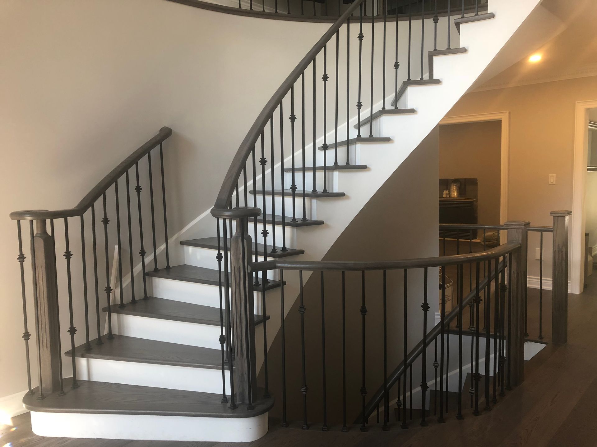 A curved staircase with a wrought iron railing in a house