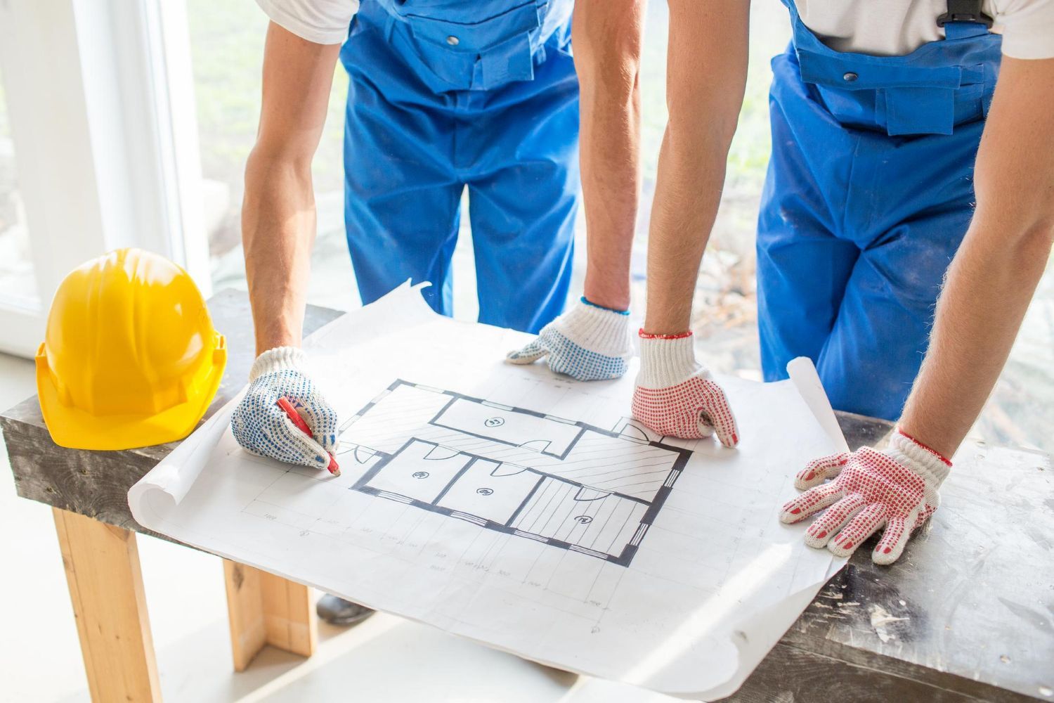 Two construction workers are looking at a blueprint of a house.