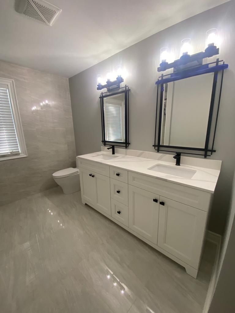 Modern bathroom with white double vanity, two mirrors, and gray walls and floor.