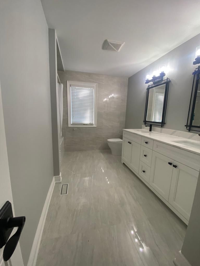 Modern bathroom with white vanity, gray tile floor, and a window.