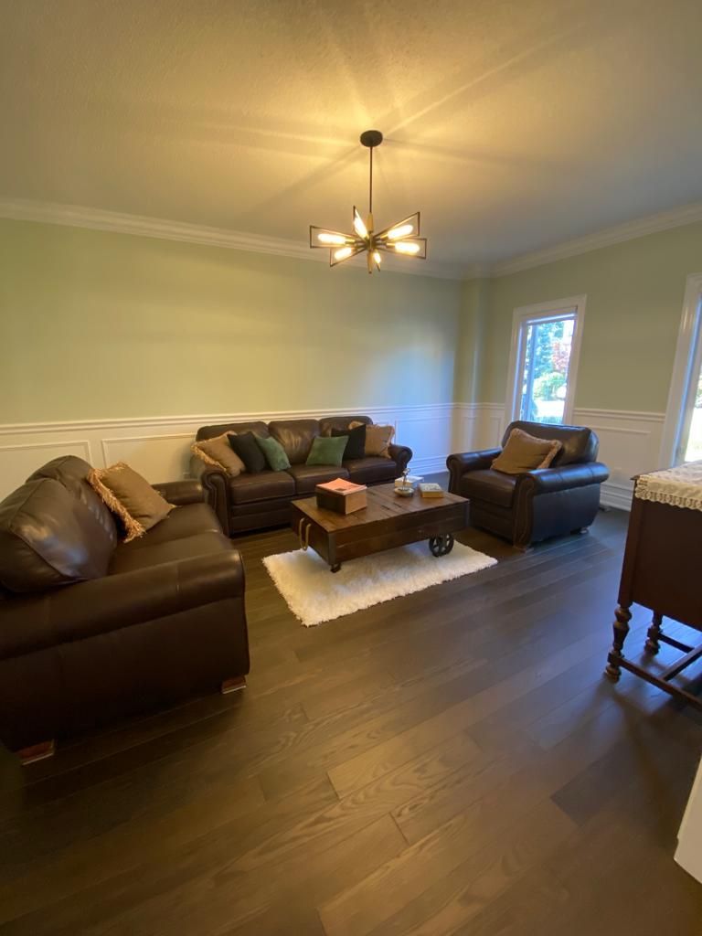 Living room with dark brown leather furniture, light green walls, and dark wood floors.