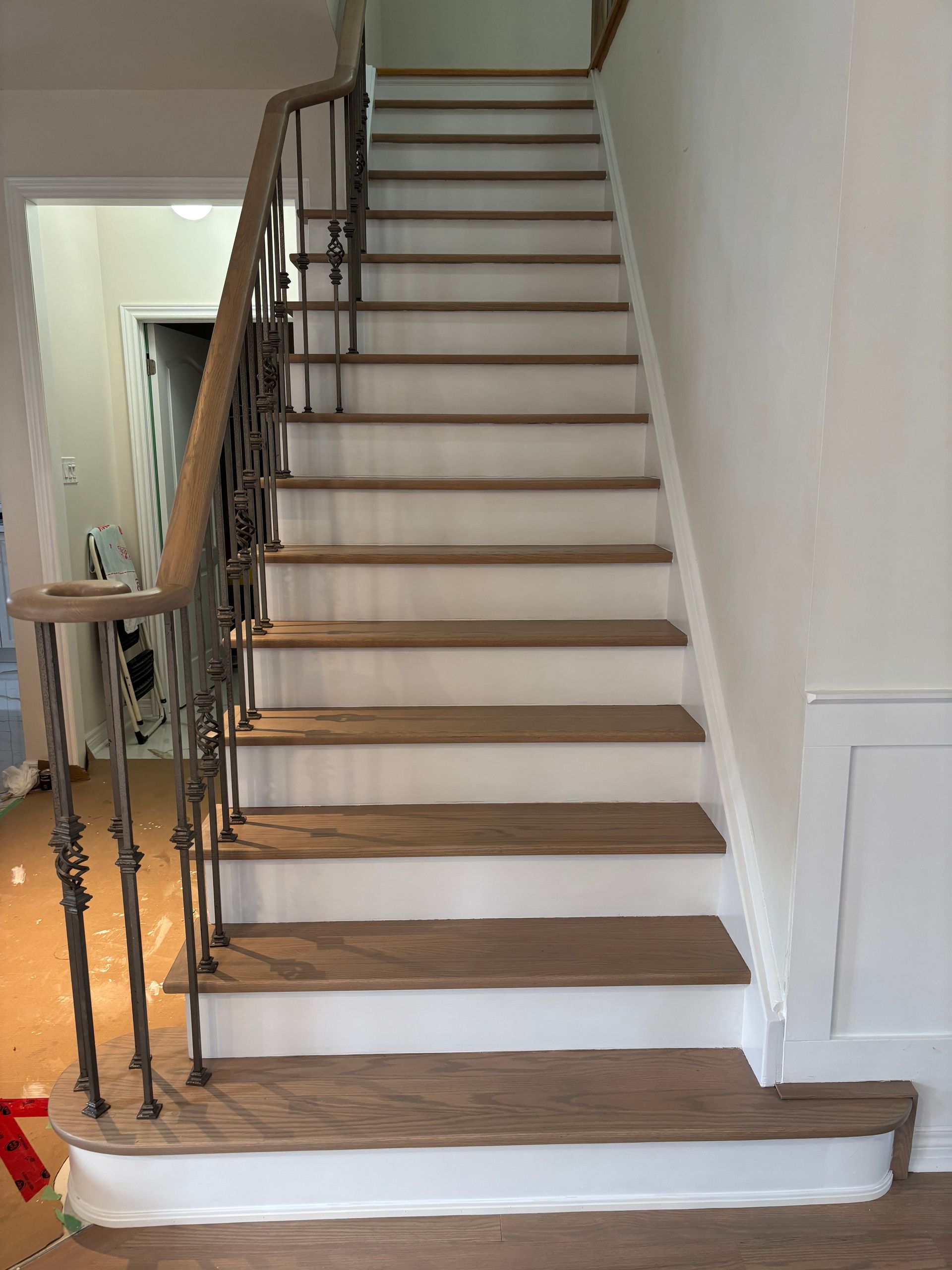 Wooden staircase with decorative iron railing and white risers.