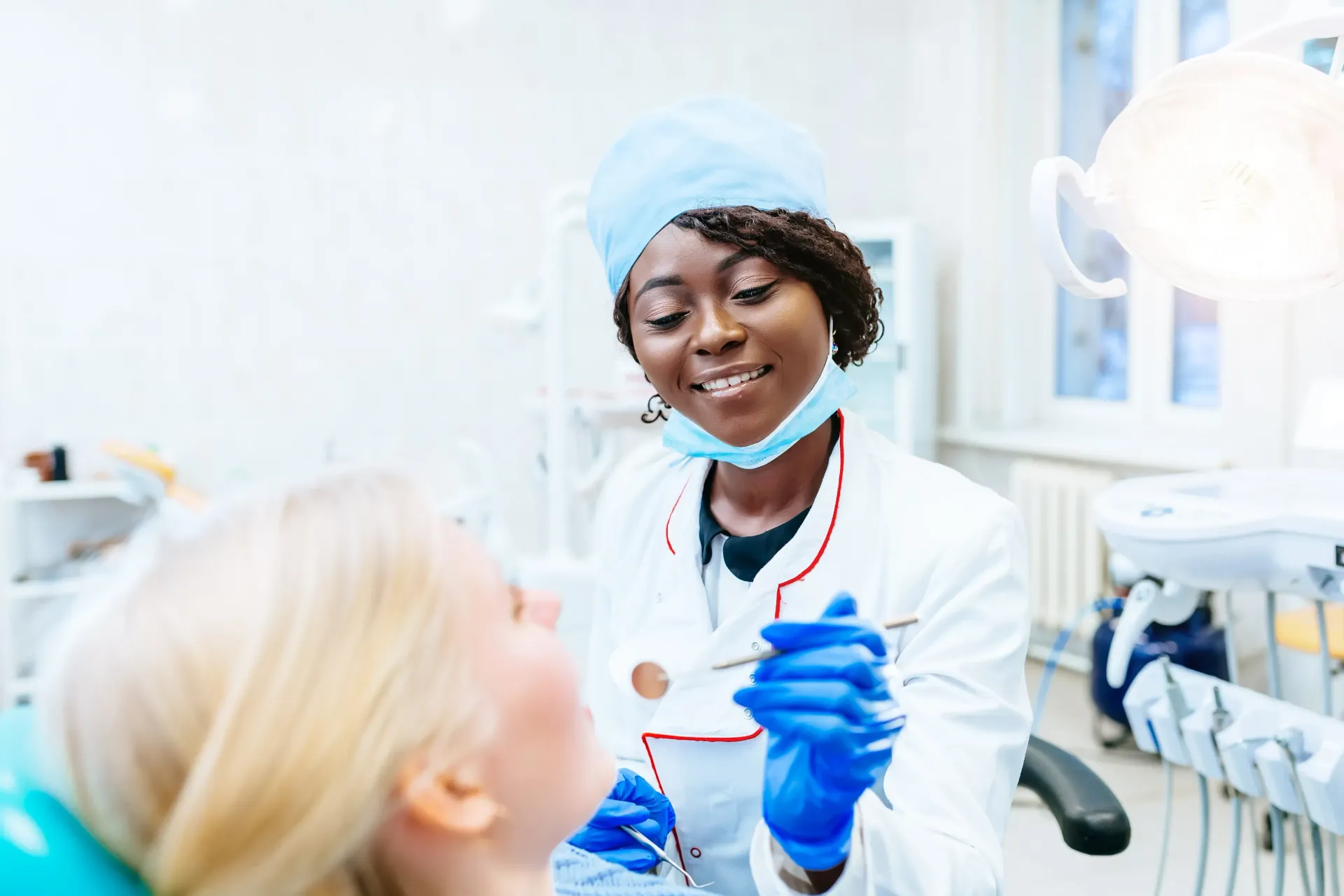 Dentist examining patient's teeth in a dental office. Doctor smiles; both are Caucasian, fair-skinned.