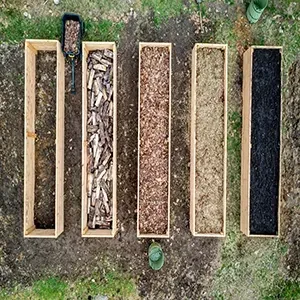 Six rectangular bins of organic materials arranged on grass, viewed from above.