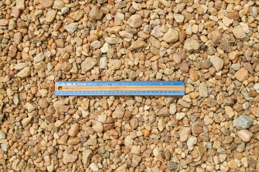 Blue measuring ruler on tan gravel ground
