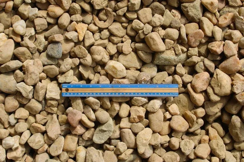 Blue and orange ruler on a bed of tan gravel stones
