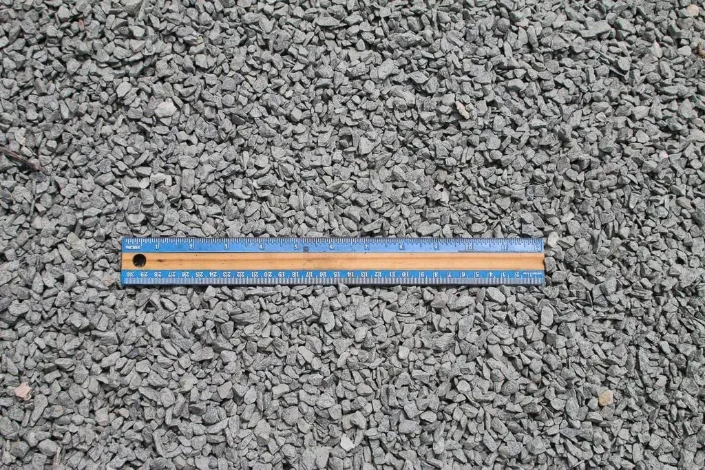 Blue and orange ruler lying on gray gravel background