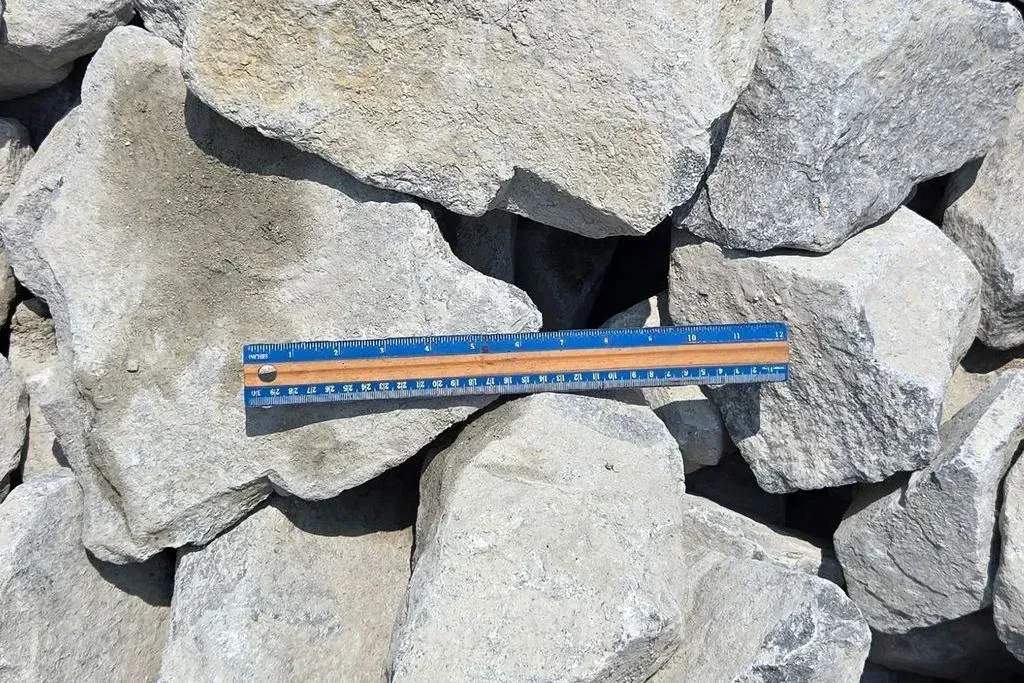 Orange-and-blue measuring sticks laid across a pile of gray rocks