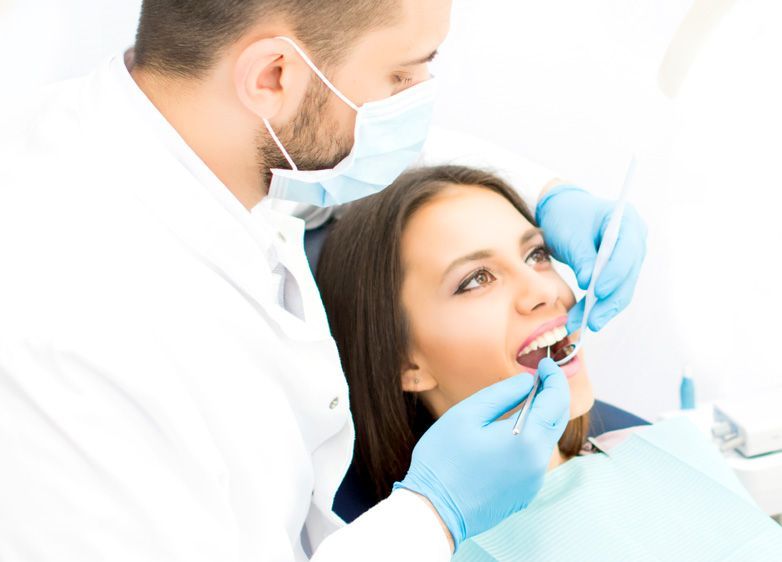 A woman is getting her teeth examined by a dentist.