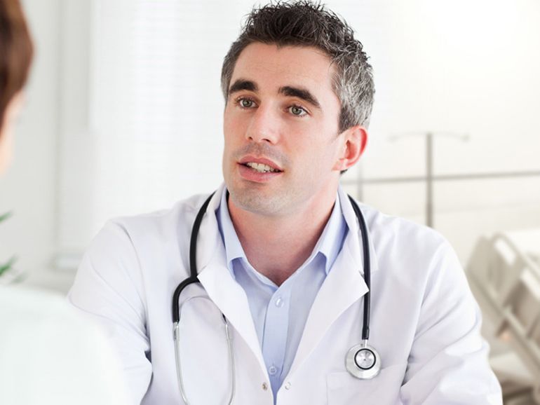 A doctor with a stethoscope around his neck is talking to a patient.