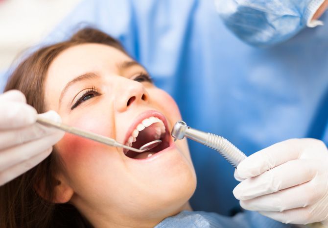 A woman is getting her teeth examined by a dentist.