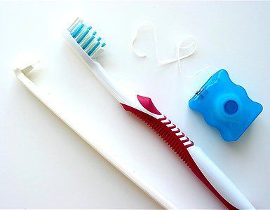 A toothbrush and floss on a white surface