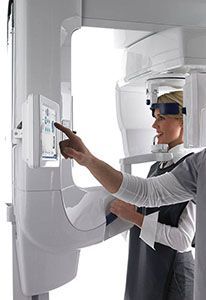 A woman is using a panoramic x-ray machine in a dental office.