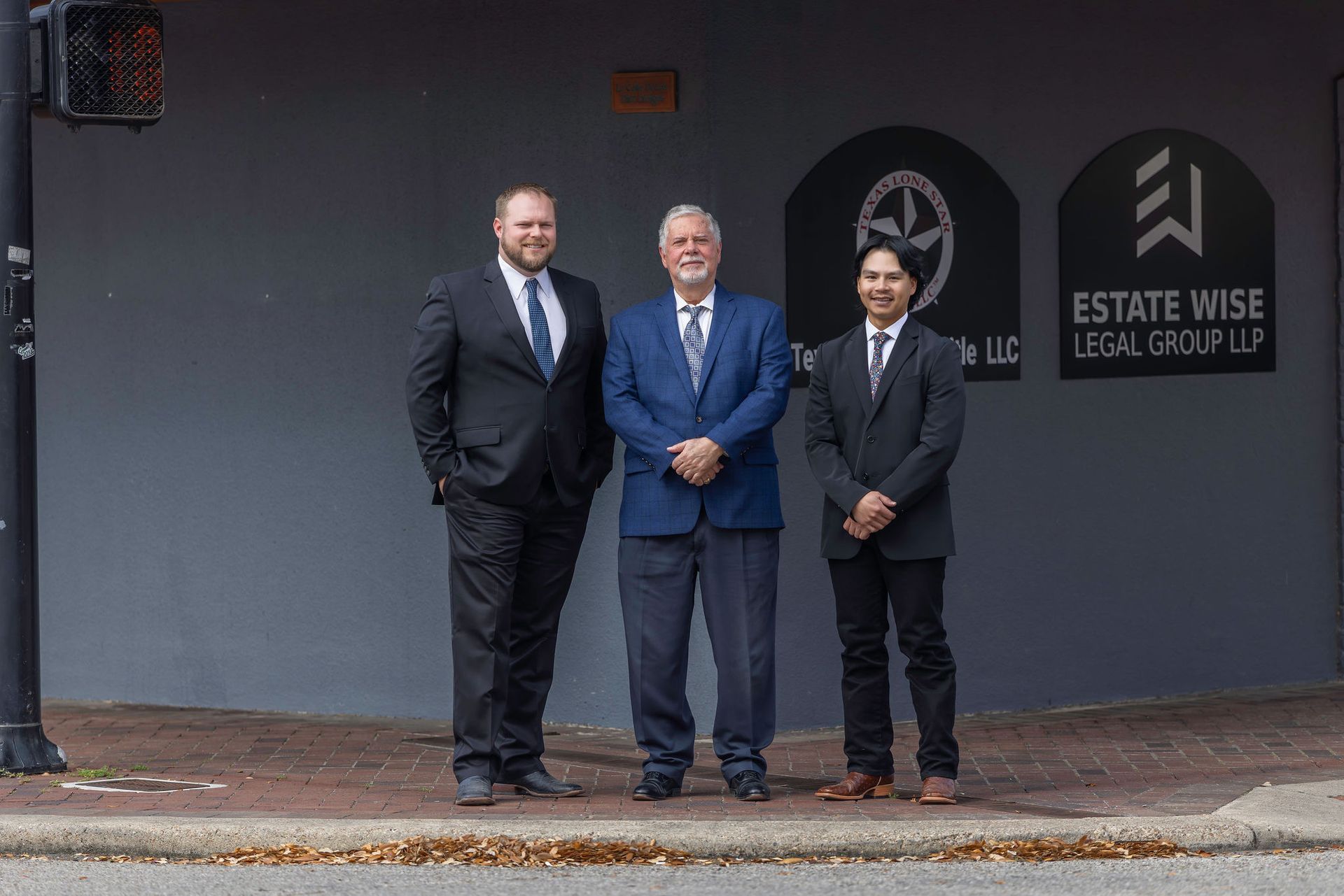 Three men in suits standing outside Estate Wise Lettings & Property on a sidewalk.