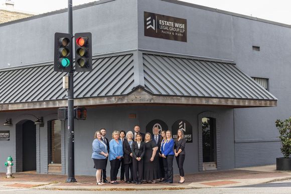 Group posing outside a gray building at a street corner, near a traffic light.