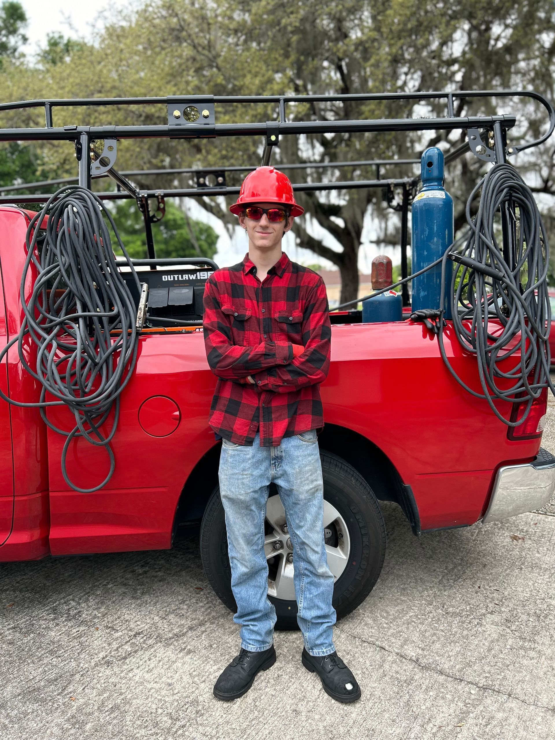A man wearing a hard hat is standing in front of a red truck.