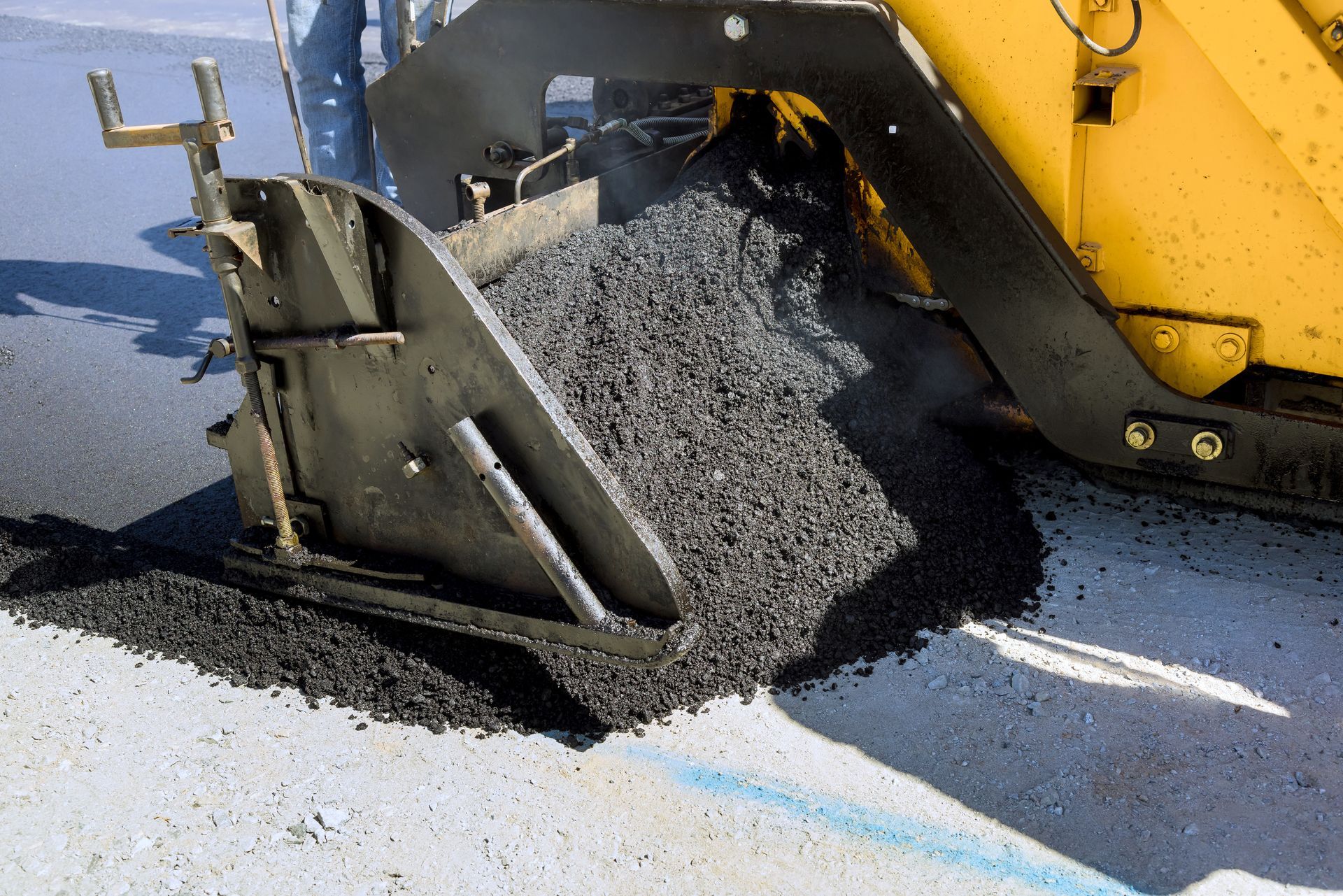Paver machine discharging hot-mix asphalt during a driveway paving project. Paver machine discharging hot-mix asphalt during a driveway paving project.
