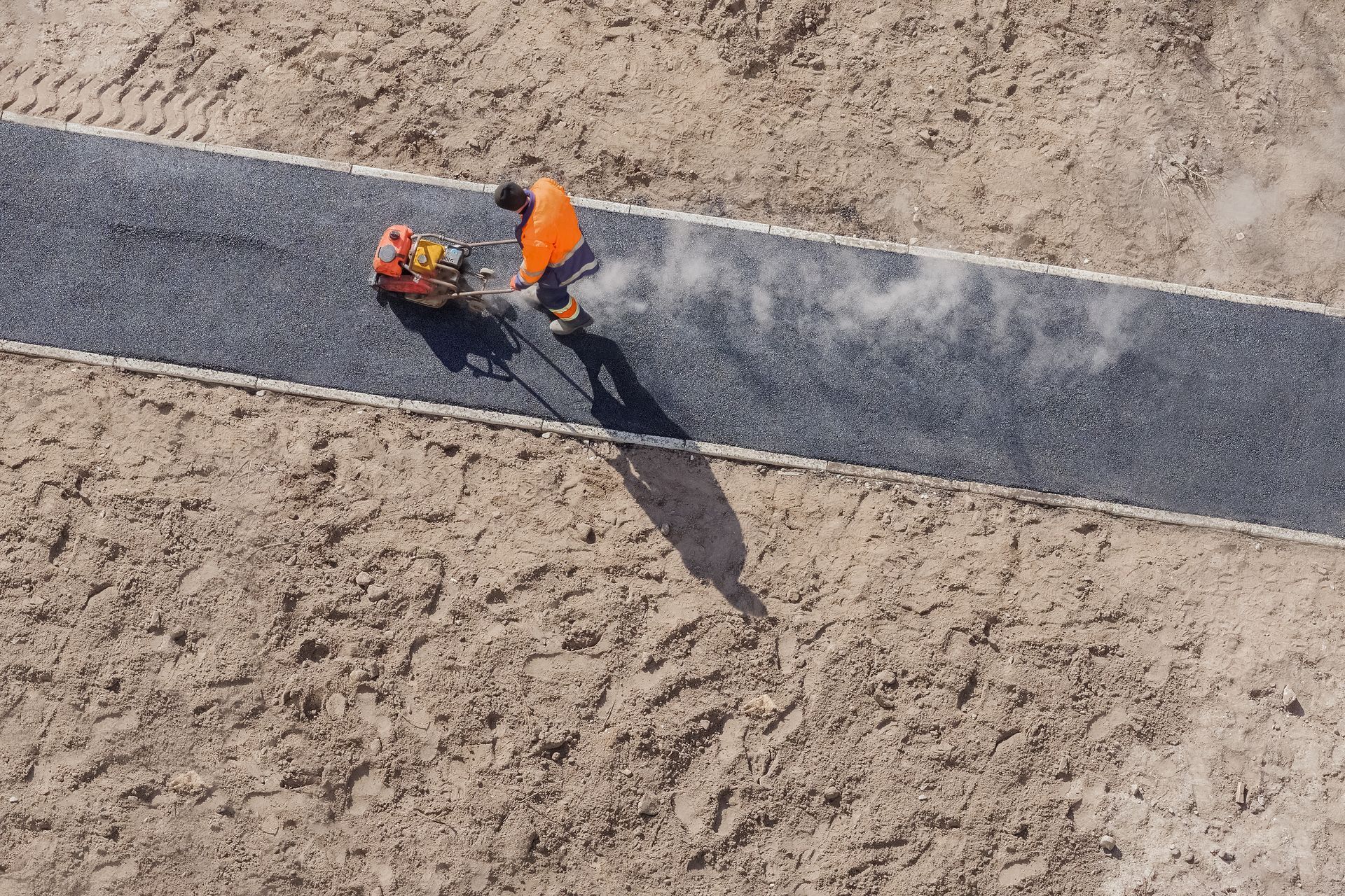Freshly compacted hot-mix asphalt driveway with a smooth dark finish and precisely trimmed edges.