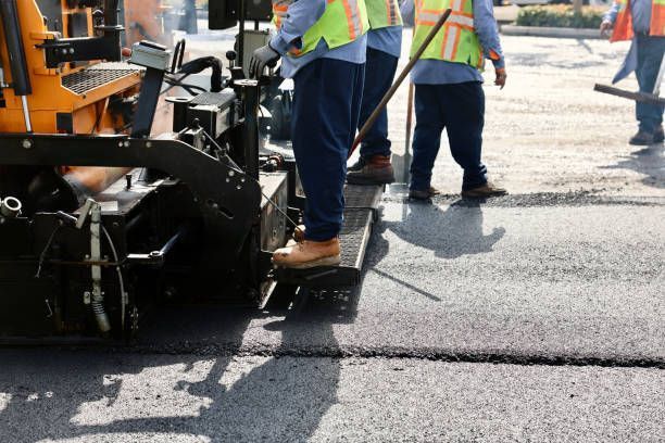 Road construction crew paving asphalt, wearing safety vests and work boots.