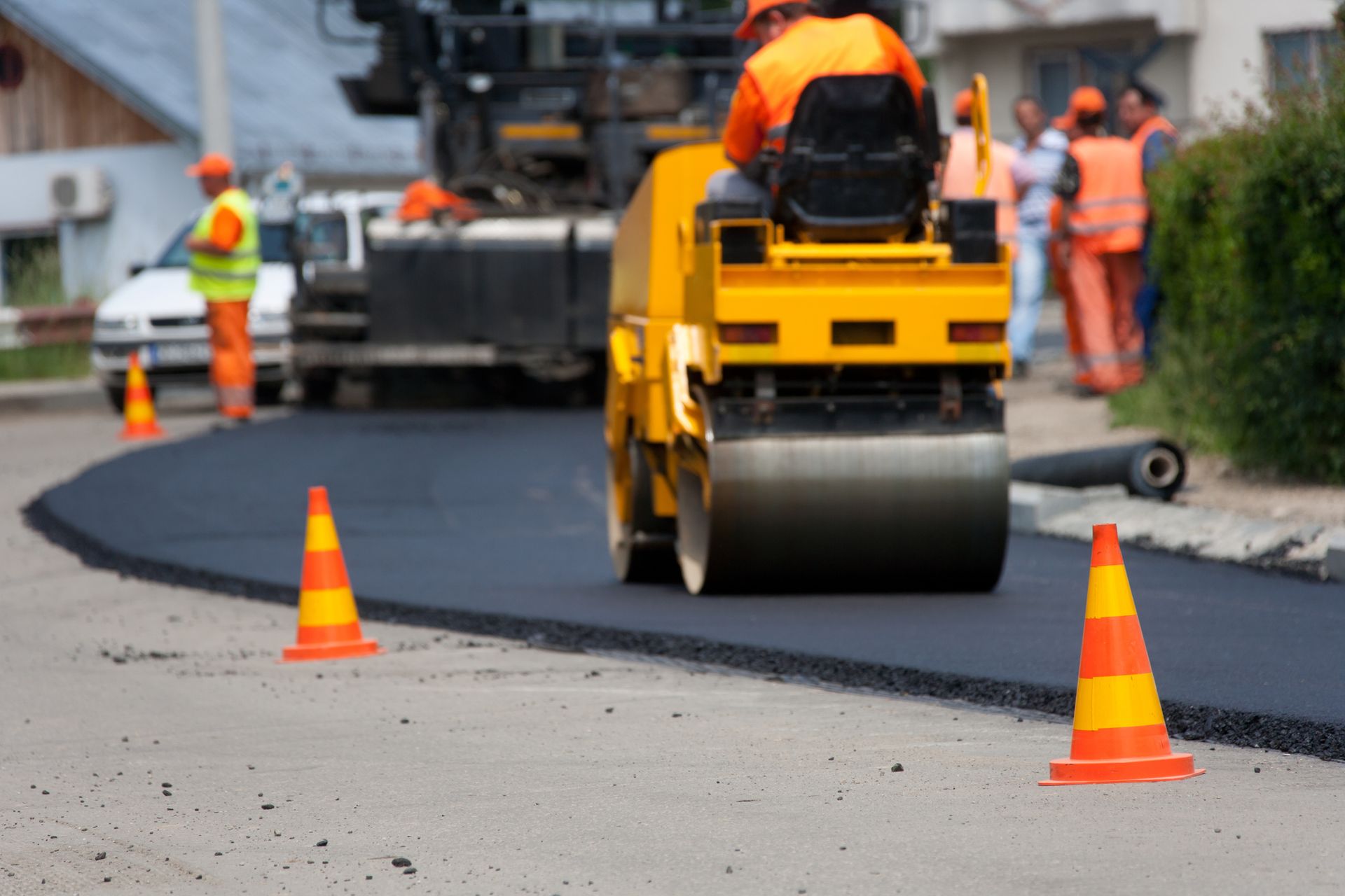 Residential paving contractors use a spreader to lay the first layer of asphalt on a city street.