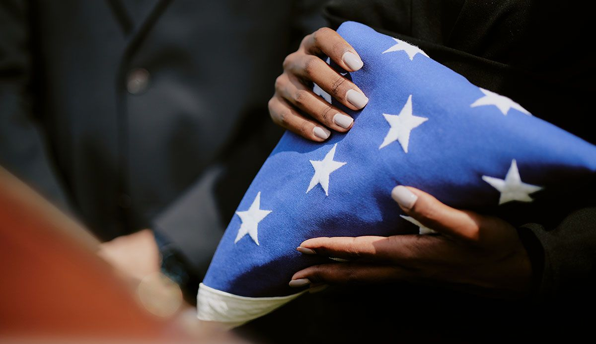 Hands carefully folding the American flag, blue field with white stars visible.