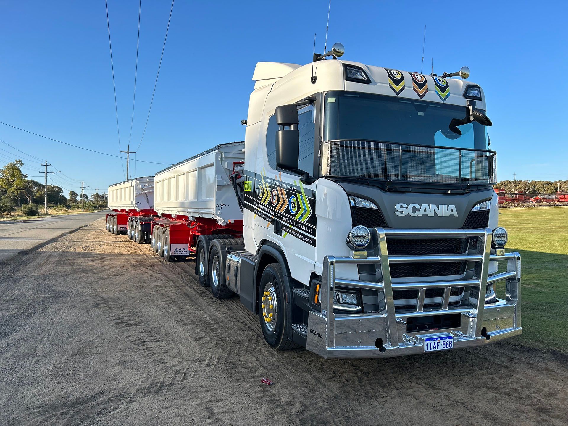 A white truck with a trailer is parked on the side of the road