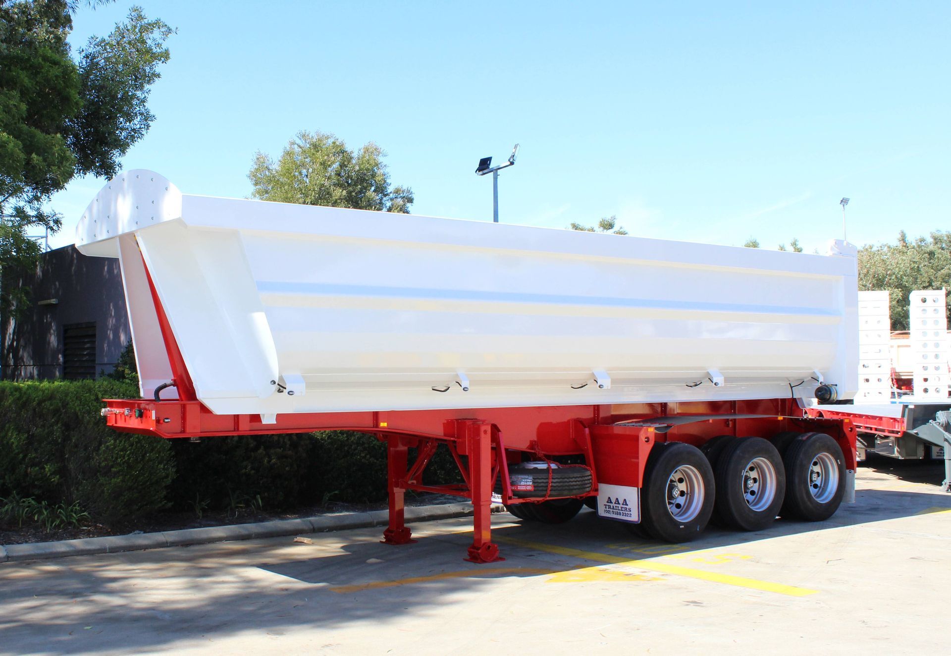 A red and white rock (end) tipper is parked in a parking lot.