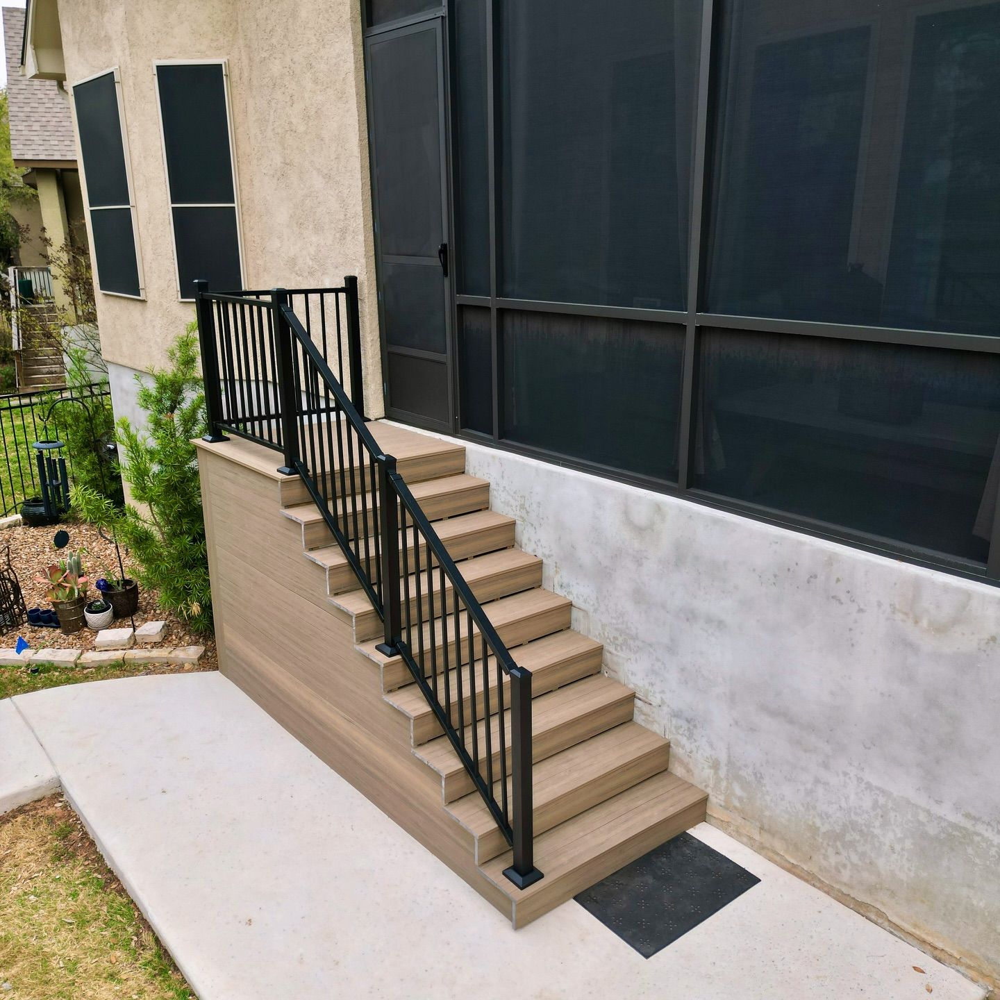 Outdoor stairway with black railing beside a building with large dark windows and beige walls