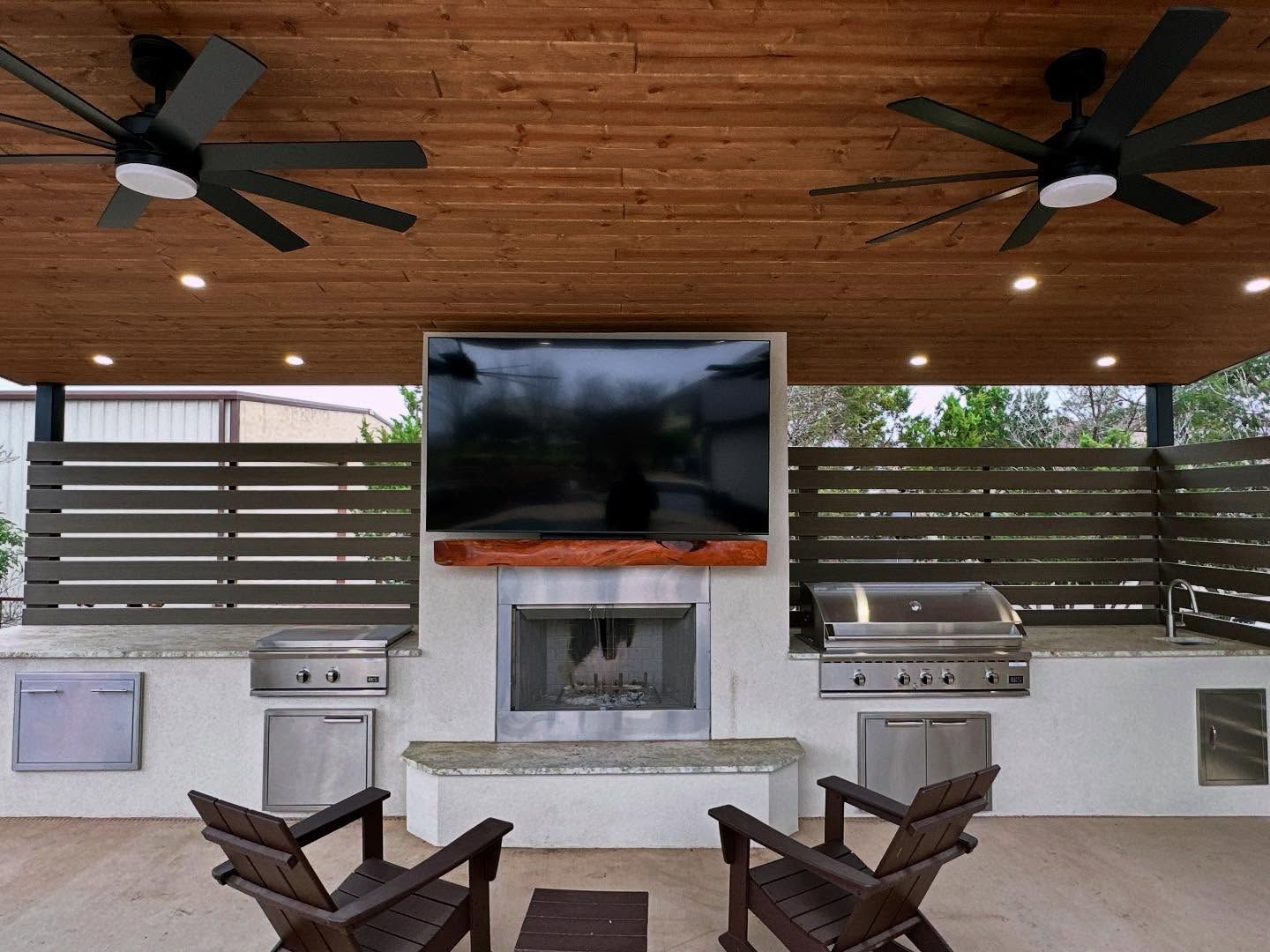 Covered patio with wood ceiling, ceiling fans, fireplace, grill, TV, and lounge chairs.
