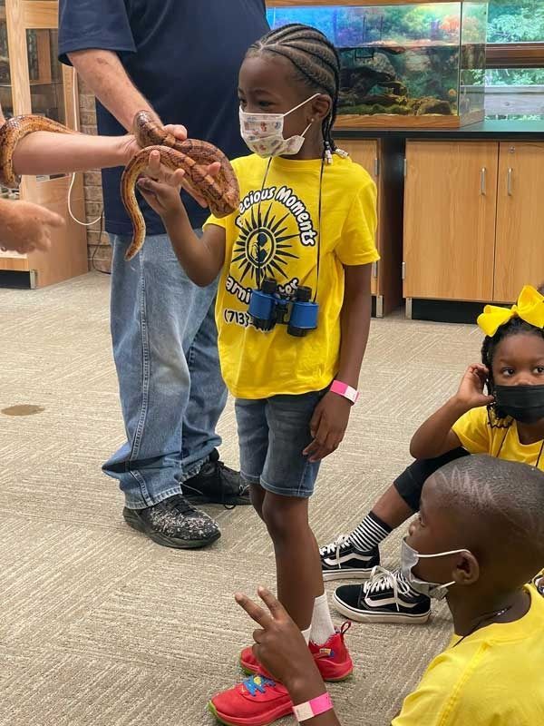 Child in yellow shirt holding a turtle shell while others watch in a classroom.