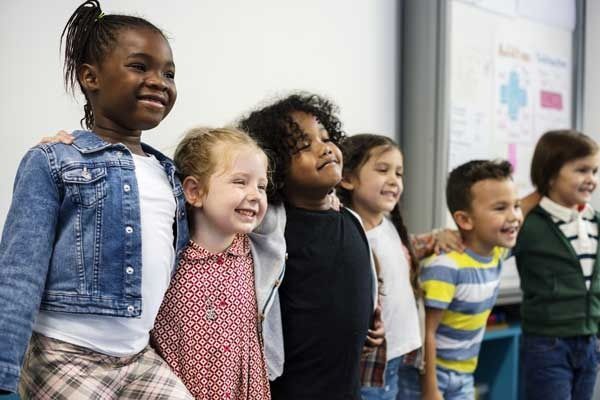 A line of smiling children standing together in a classroom.