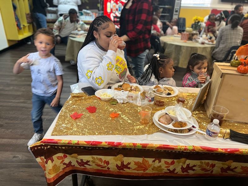 People at a buffet table in a decorated hall, with plates of food and a child walking nearby