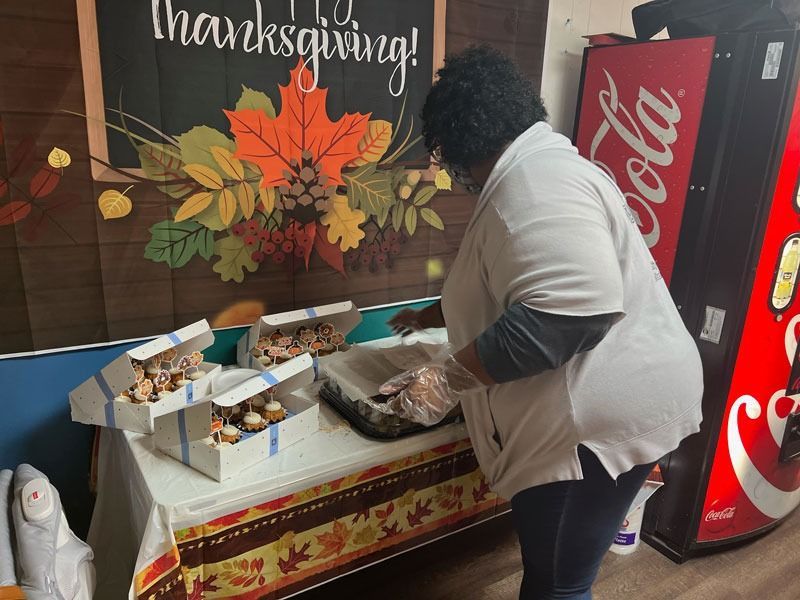 Person serving food at a Thanksgiving table beside a red Coca-Cola vending machine