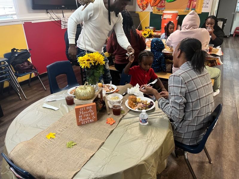 People gathered around a table with food and flowers in a brightly decorated room