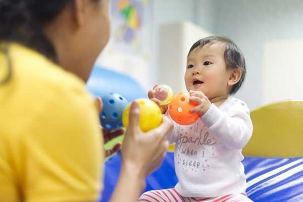 Adult and baby playing with colorful toys on a blue mat