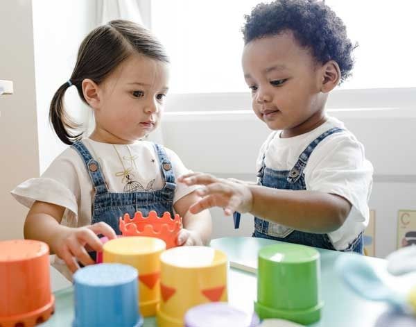 Two children playing with colorful stacking cups at a table