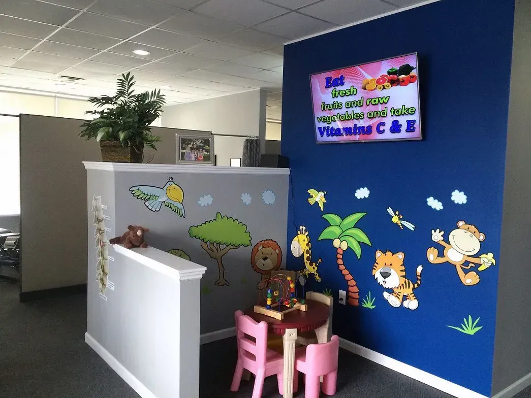 Play area with jungle-themed wall decorations, small table, and chairs in an office setting.