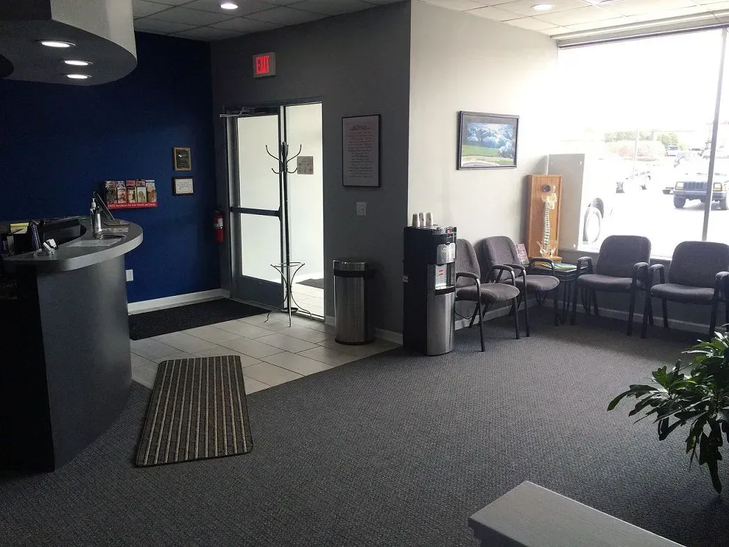Waiting room with chairs, entrance, reception desk, and large window.