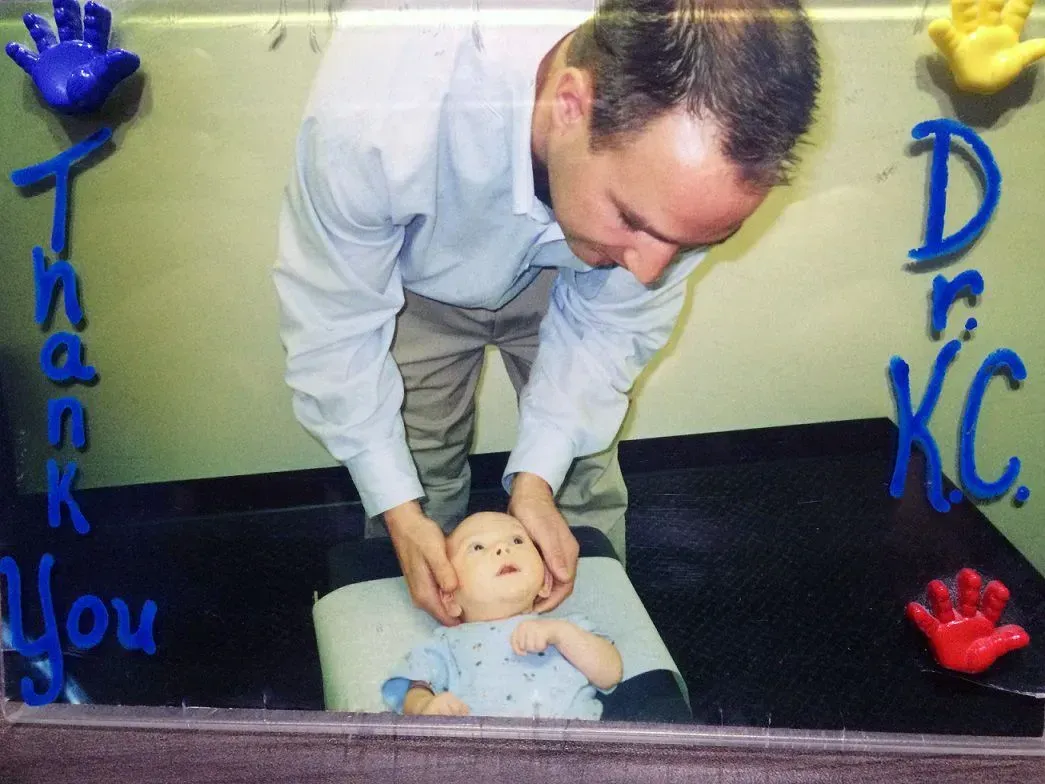 Man with baby, touching its head. Blue and red handprints and 
