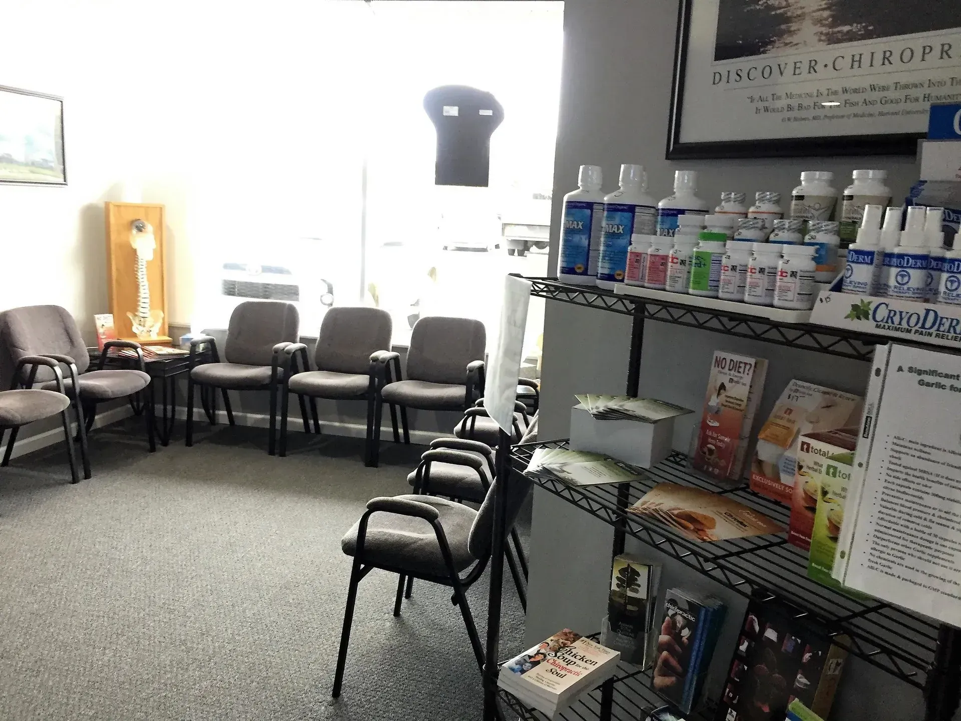 Waiting room with chairs, shelves of products, and a window.