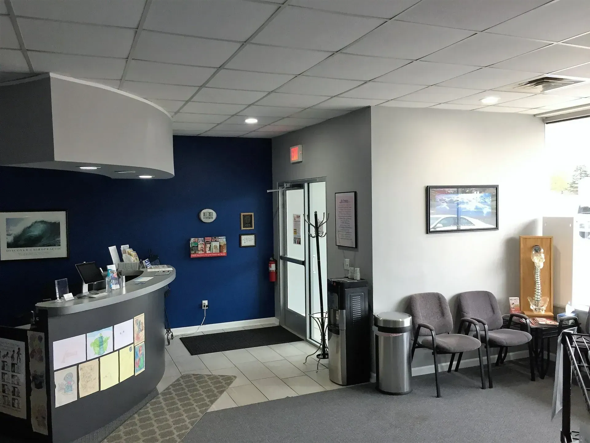 Reception area with curved desk, blue walls, seating, and exit door.