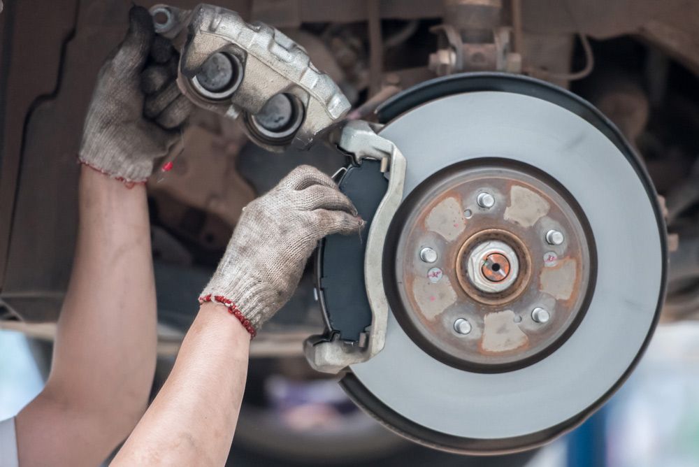 A Person Is Fixing A Brake Pad On A Car — MTM Automotive in Bentley Park, QLD