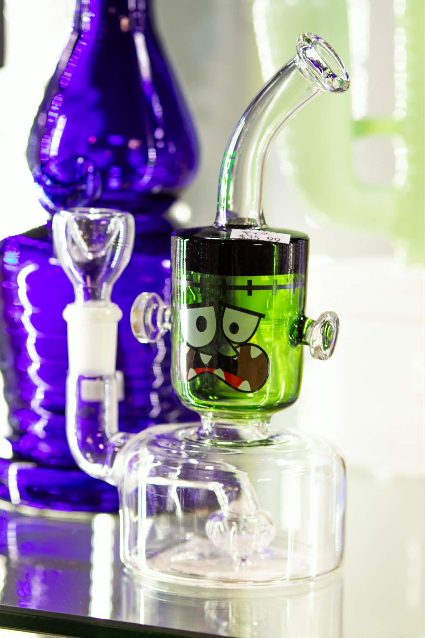 Colorful glass hookah with purple and green accents on a clear surface