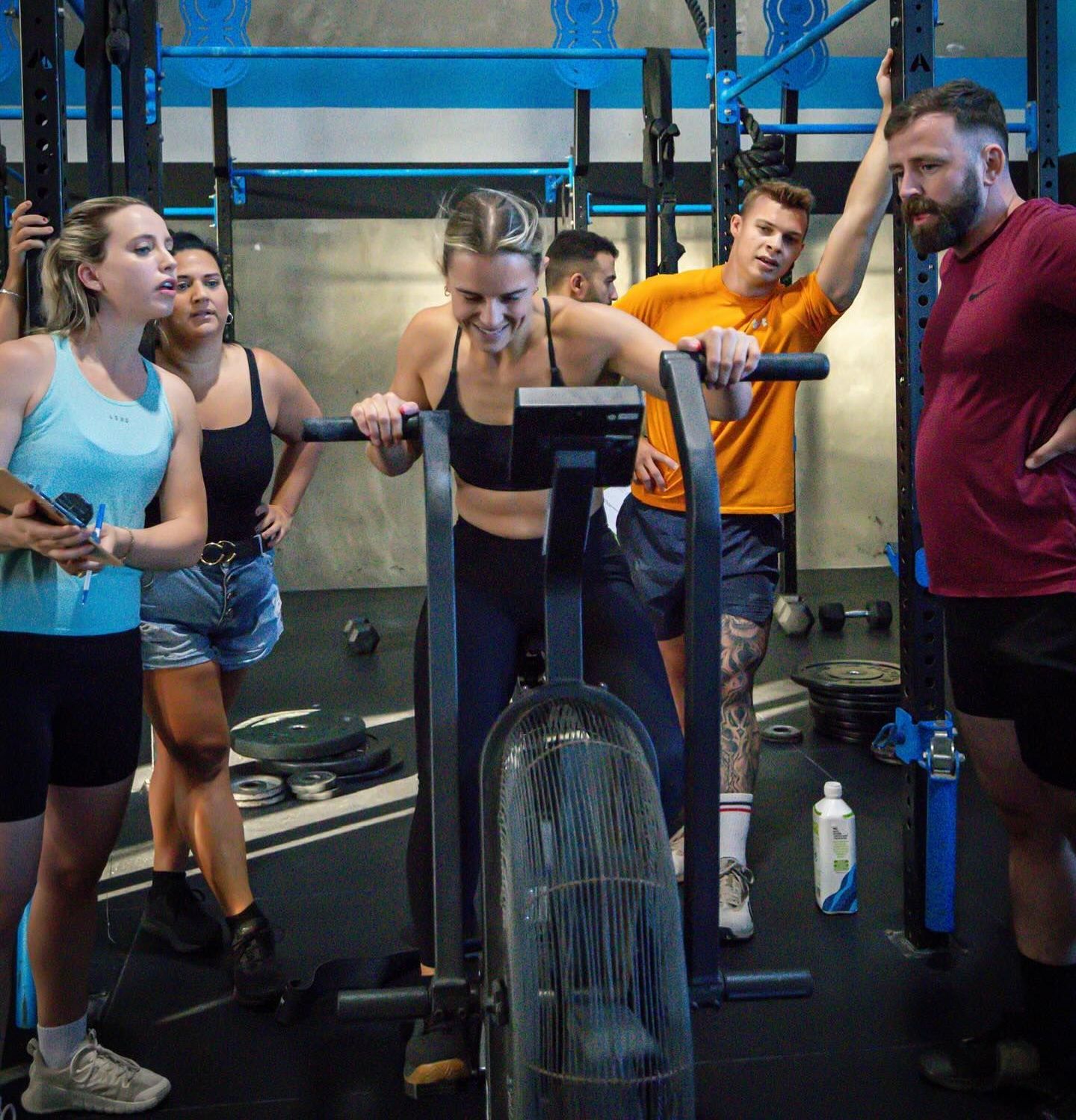 A group of people are standing around a machine in a gym at Rebuild Health and Fitness in Wynnum West & Capalaba, QLD