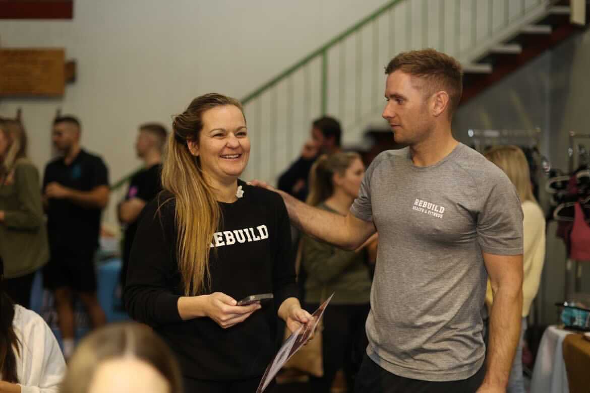 Woman in jumper smiles with coach having reassuring hand on shoulder
