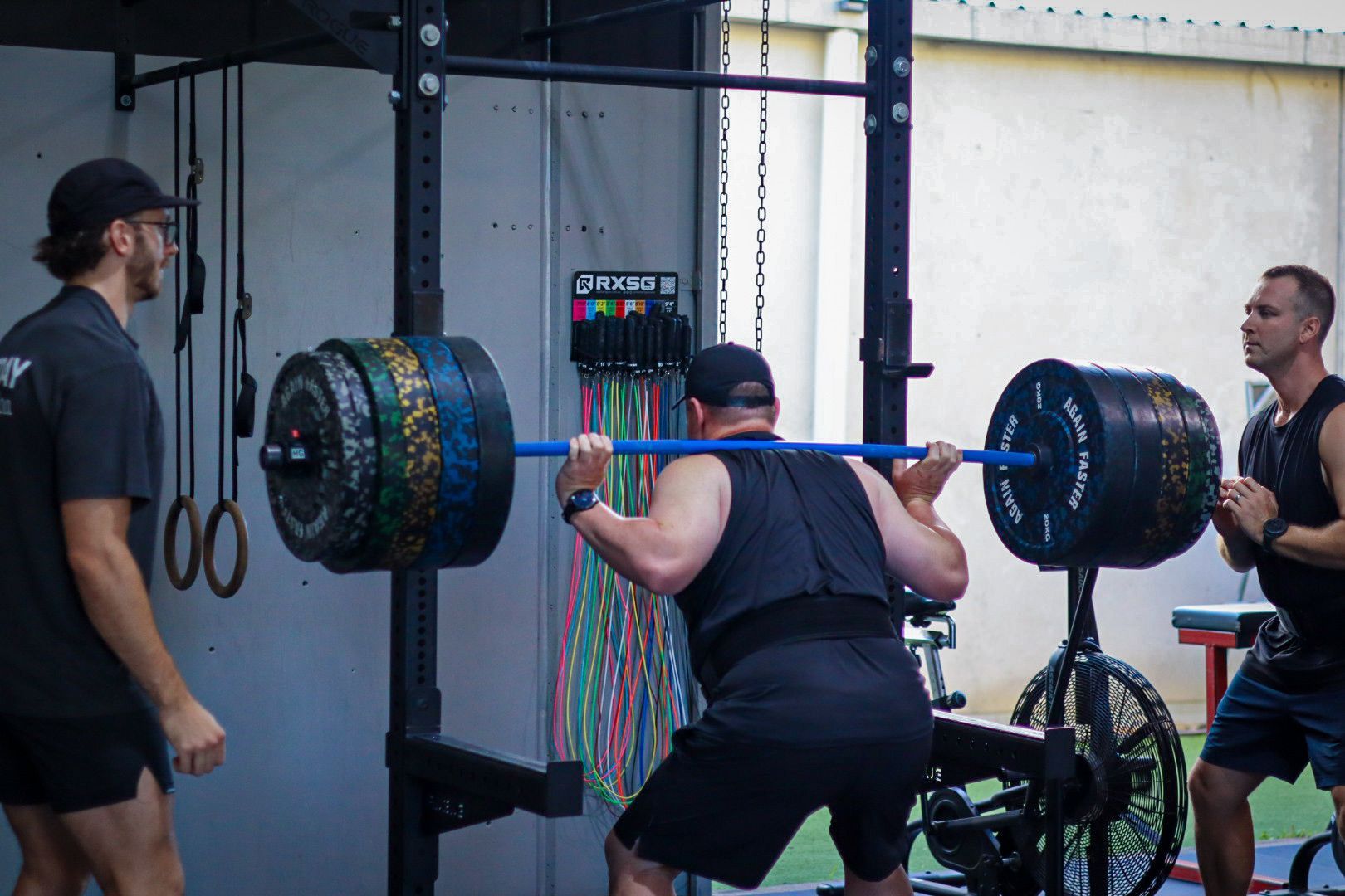 A man is squatting with a barbell in a gym at Rebuild Health and Fitness in Wynnum West & Capalaba, QLD