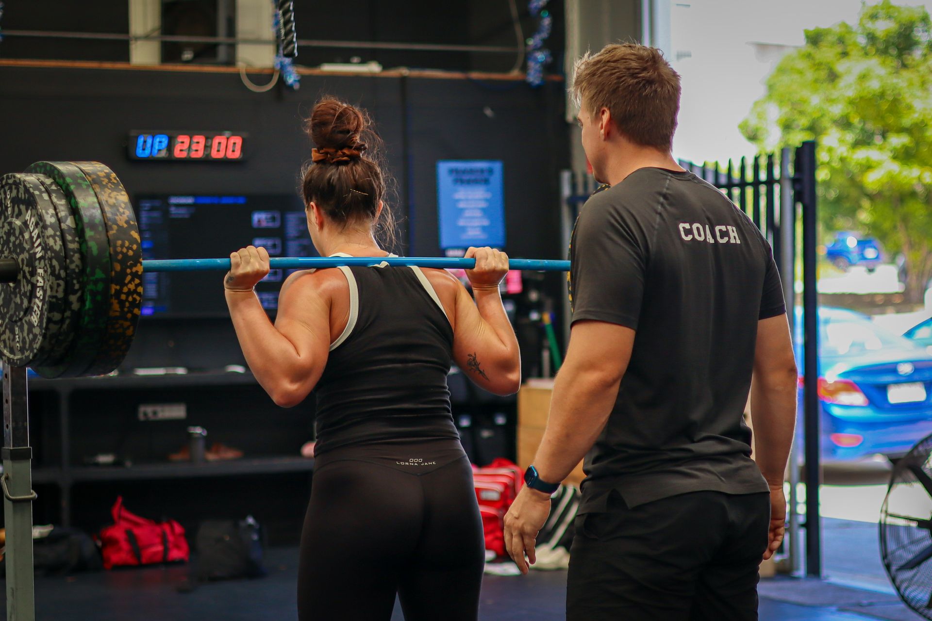 A man and a woman are squatting with a barbell in a gym at Rebuild Health and Fitness in Wynnum West & Capalaba, QLD