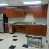 Empty kitchen with wood cabinets, stainless steel sink, and black-and-white tile floor