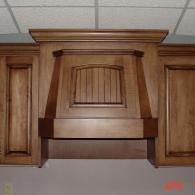 Dark wooden fireplace mantel with decorative items and a lit fire in the hearth