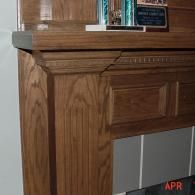 Close-up of a wooden mantel or fireplace surround with a shelf and framed items on top